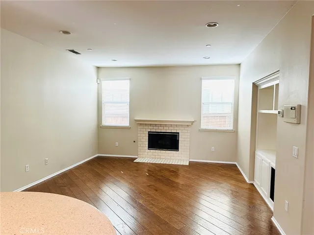 an empty room with wooden floor and a fireplace