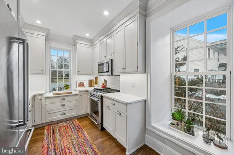 a kitchen with white cabinets and window