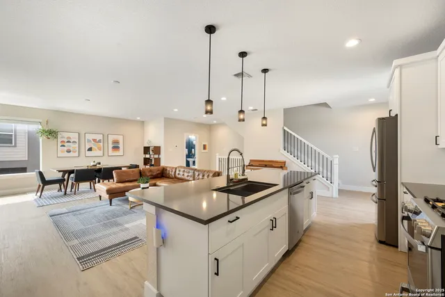 a kitchen with stainless steel appliances granite countertop a sink a stove and a wooden floors