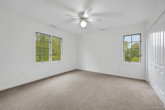 an empty room with windows and fan