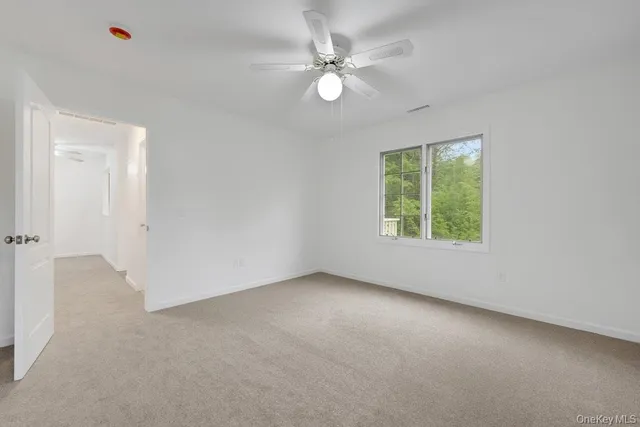 an empty room with windows and ceiling fan