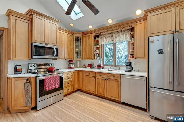 a kitchen with stainless steel appliances granite countertop a refrigerator a stove top oven a sink and dishwasher with wooden floor