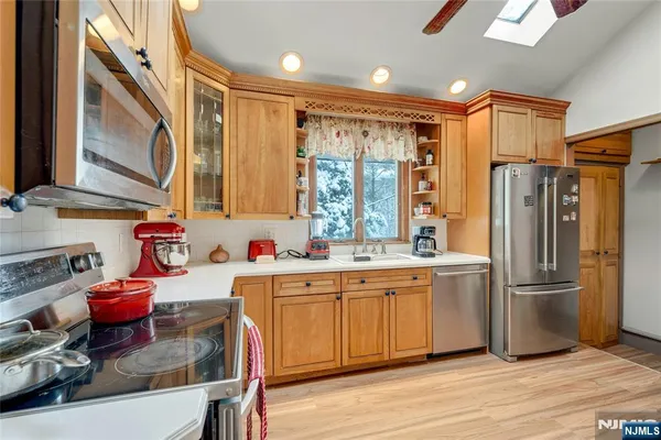 a kitchen with stainless steel appliances granite countertop a refrigerator a sink dishwasher a stove and white countertops with wooden floor