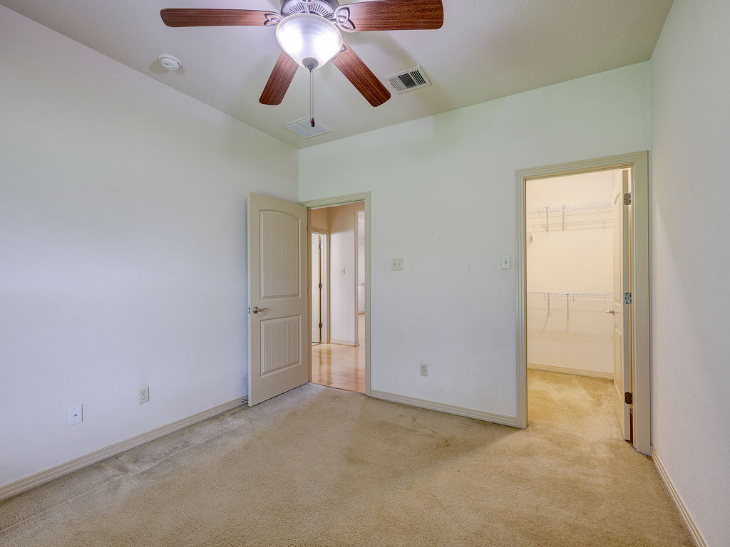 9707 Anderson Mill Road, Unit 22 Austin, TX 78750 - Photo 25 of 39 A comfortable bedroom features carpeted floors, a ceiling fan, and convenient access to a walk-in closet.