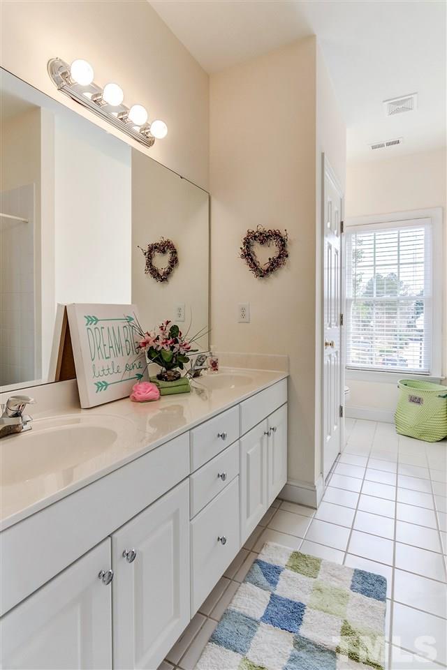2401 Carruthers Court Raleigh, NC 27615 - Photo 22 of 25 a spacious bathroom with a double vanity sink a mirror and a bathtub