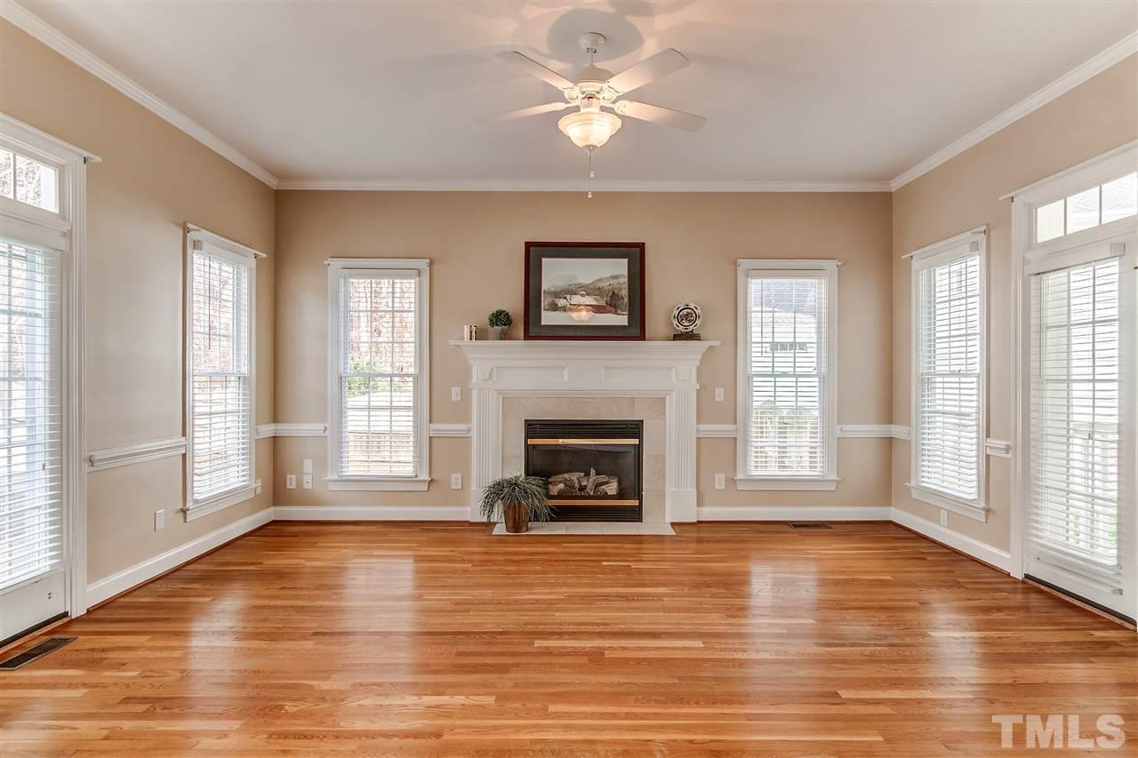 2401 Carruthers Court Raleigh, NC 27615 - Photo 6 of 25 an empty room with windows fireplace and wooden floor