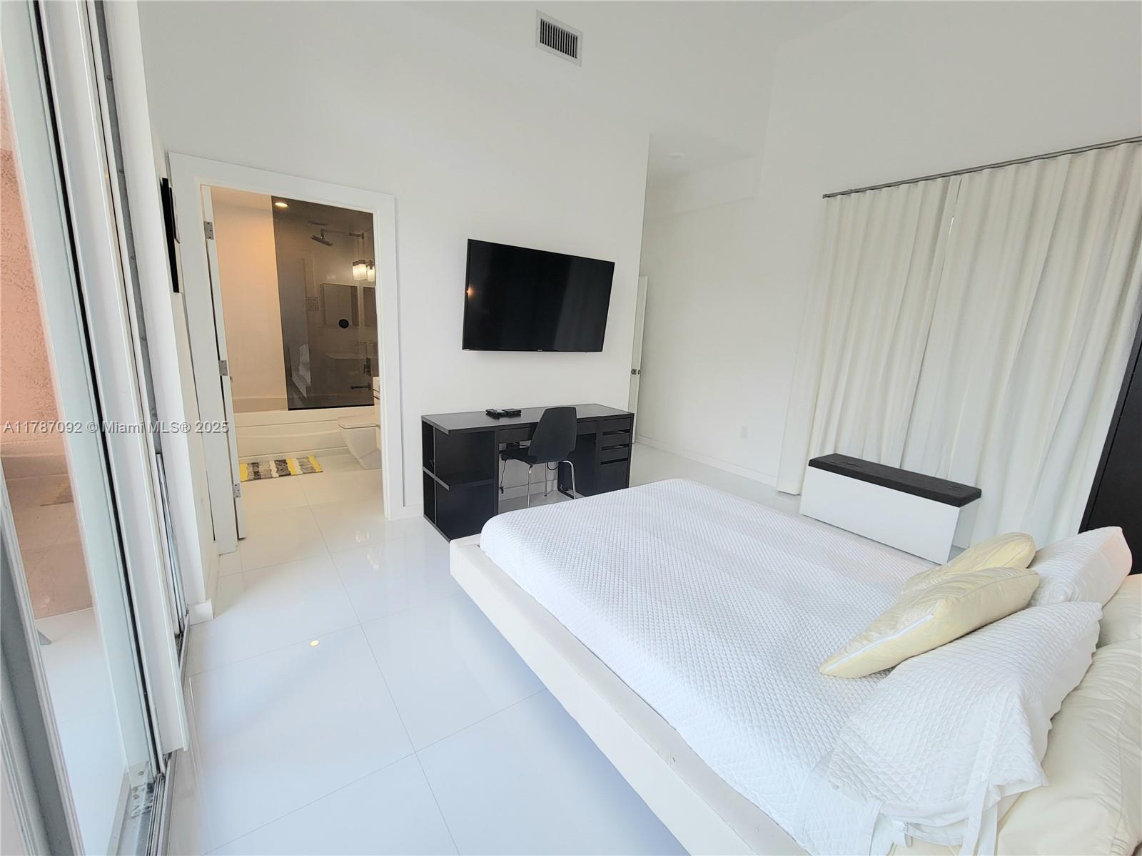 90 Alton Road, Unit 1 Miami Beach, FL 33139 - Photo 18 of 36 a bedroom with a bed and a flat screen tv