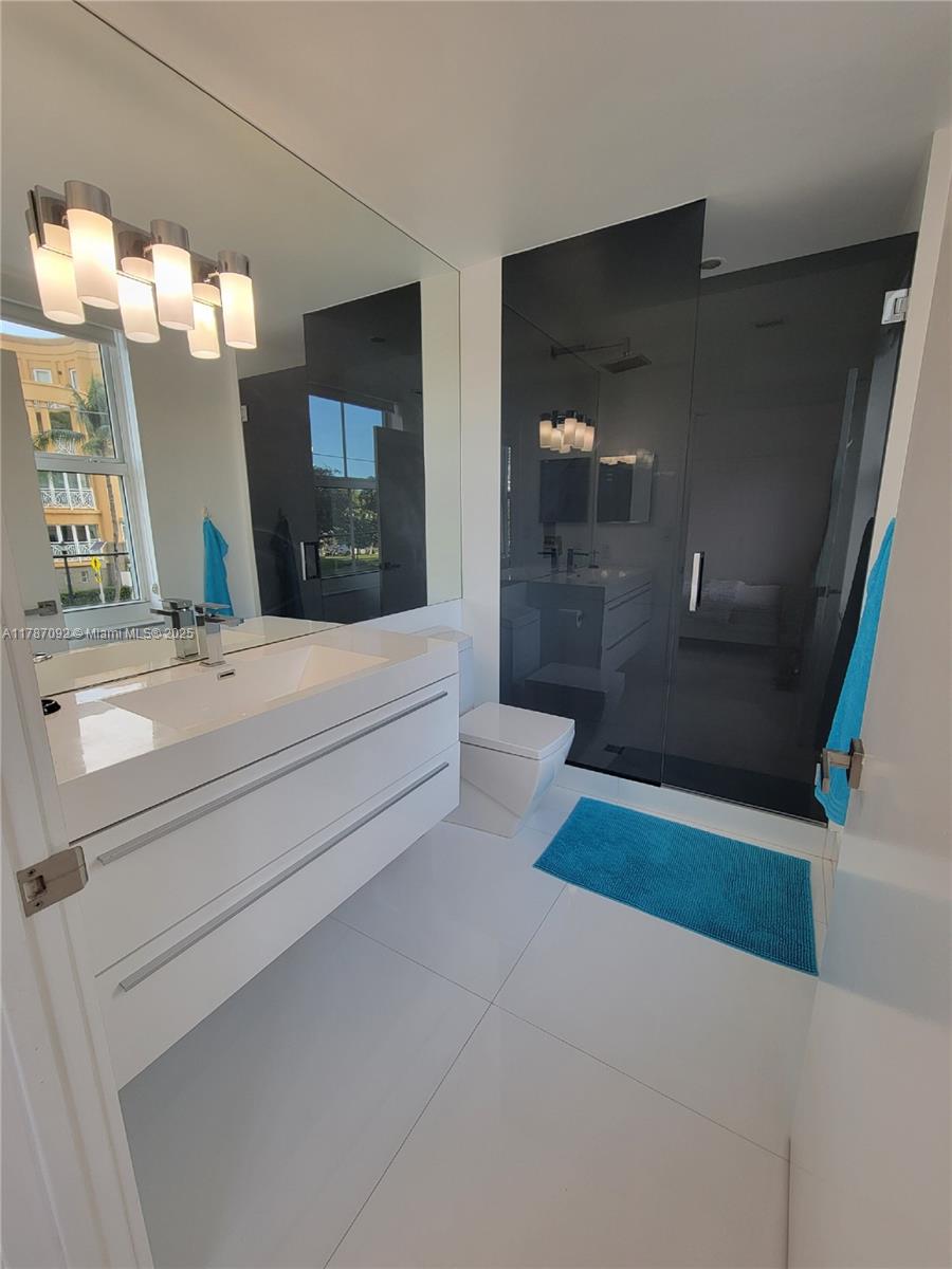 90 Alton Road, Unit 1 Miami Beach, FL 33139 - Photo 25 of 36 a bathroom with a sink a toilet and mirror