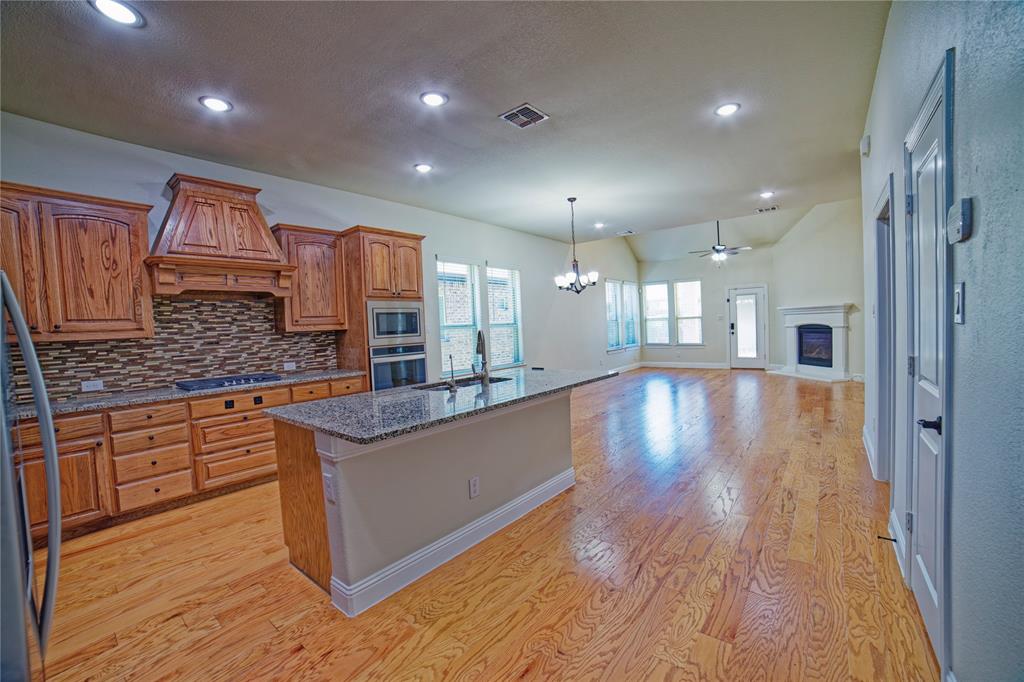 10929 Calvert Place McKinney, TX 75071 - Photo 13 of 39 a large kitchen with stainless steel appliances granite countertop a large counter top a sink and a wooden floors