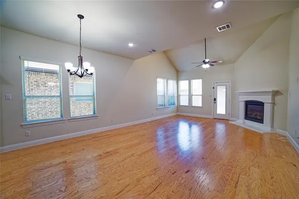 an empty room with wooden floor chandelier and fireplace