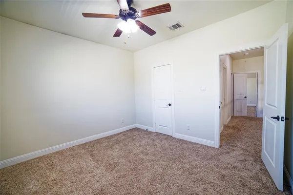 an empty room with closet and a ceiling fan