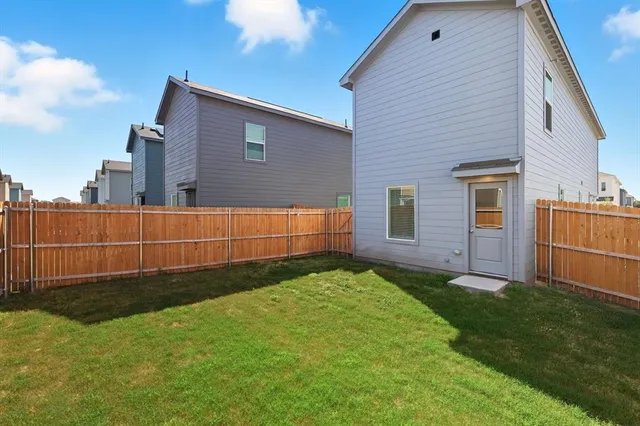 a view of backyard with barbeque grill and wooden fence