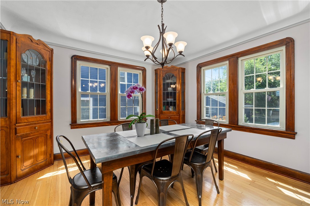 26019 Lake Road Bay Village, OH 44140 - Photo 14 of 40 Formal dining area featuring hardwood flooring, extensive natural wood trim, and a built-in corner cabinet with glass doors