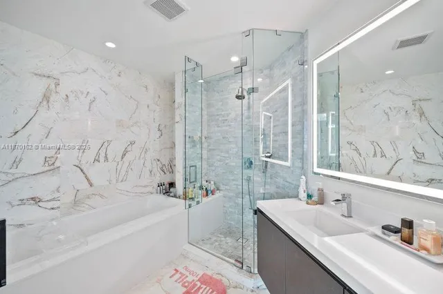 a bathroom with a granite countertop sink a mirror a bathtub and shower