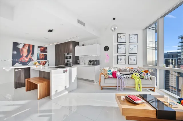 a living room with stainless steel appliances furniture and a kitchen view