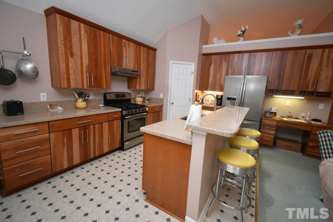 9904 Wyngate Ridge Drive Raleigh, NC 27617 - Photo 18 of 39 a kitchen with stainless steel appliances a sink a stove a refrigerator cabinets and dining table