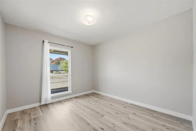 an empty room with wooden floor and window