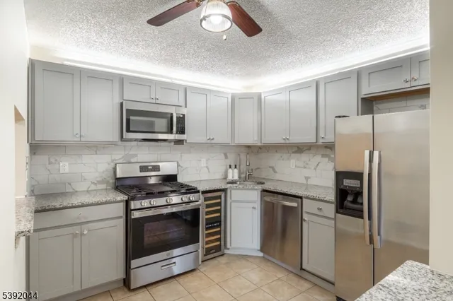 a kitchen with stainless steel appliances granite countertop a stove top oven a refrigerator and a sink
