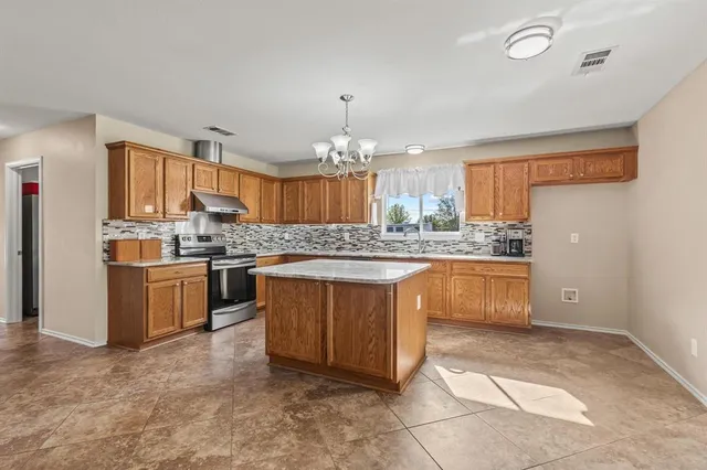 a large kitchen with kitchen island a stove a sink a oven and a dining table