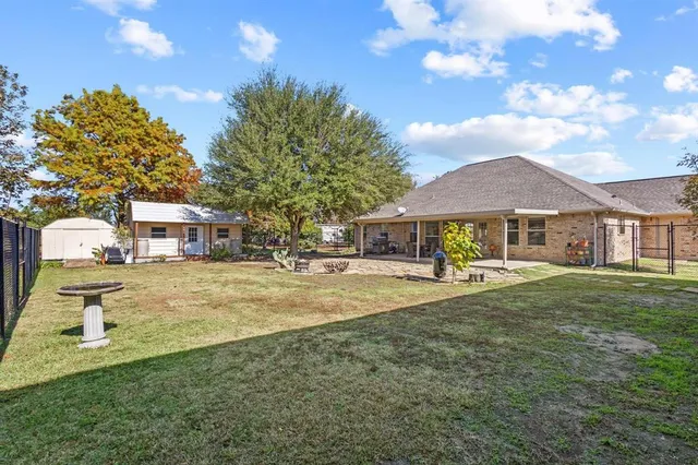 a view of a house with a yard and large tree
