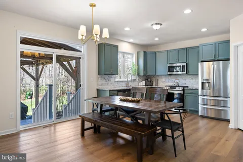 a kitchen with kitchen island granite countertop a dining table chairs refrigerator and cabinets