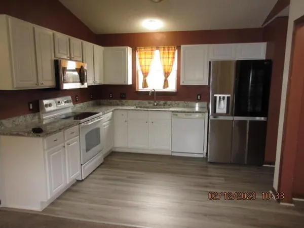 a kitchen with stainless steel appliances granite countertop a sink a stove a refrigerator and cabinets