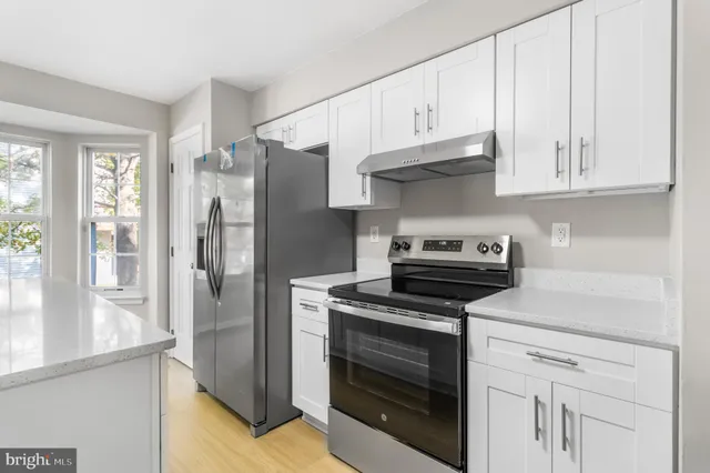 a kitchen with stainless steel appliances granite countertop white cabinets and a stove