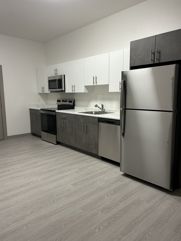 626 Main Street, Unit 203 Dennis, MA 02639 - Photo 3 of 18 a kitchen with stainless steel appliances granite countertop a refrigerator sink and white cabinets