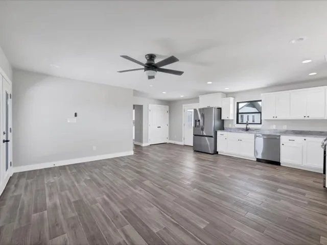 a large kitchen with granite countertop a large counter top a sink stainless steel appliances and cabinets