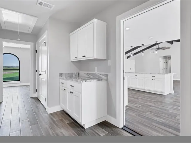 a view of an empty room with wooden floor and a ceiling fan