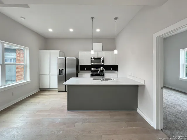 a view of kitchen with stainless steel appliances granite countertop a refrigerator and a sink