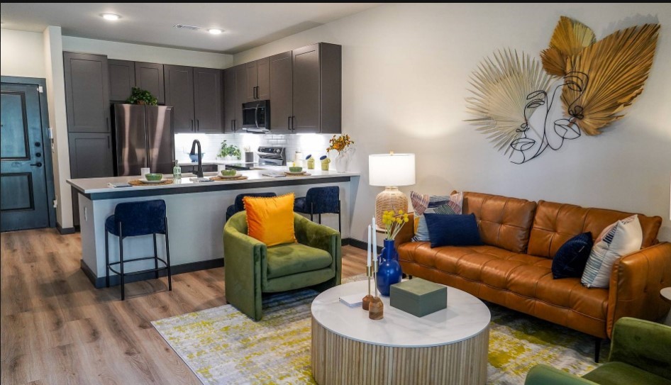 a living room with furniture kitchen view and a wooden floor