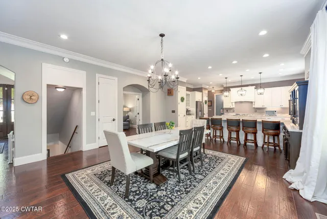 a kitchen with stainless steel appliances granite countertop a sink a stove a refrigerator cabinets and chairs