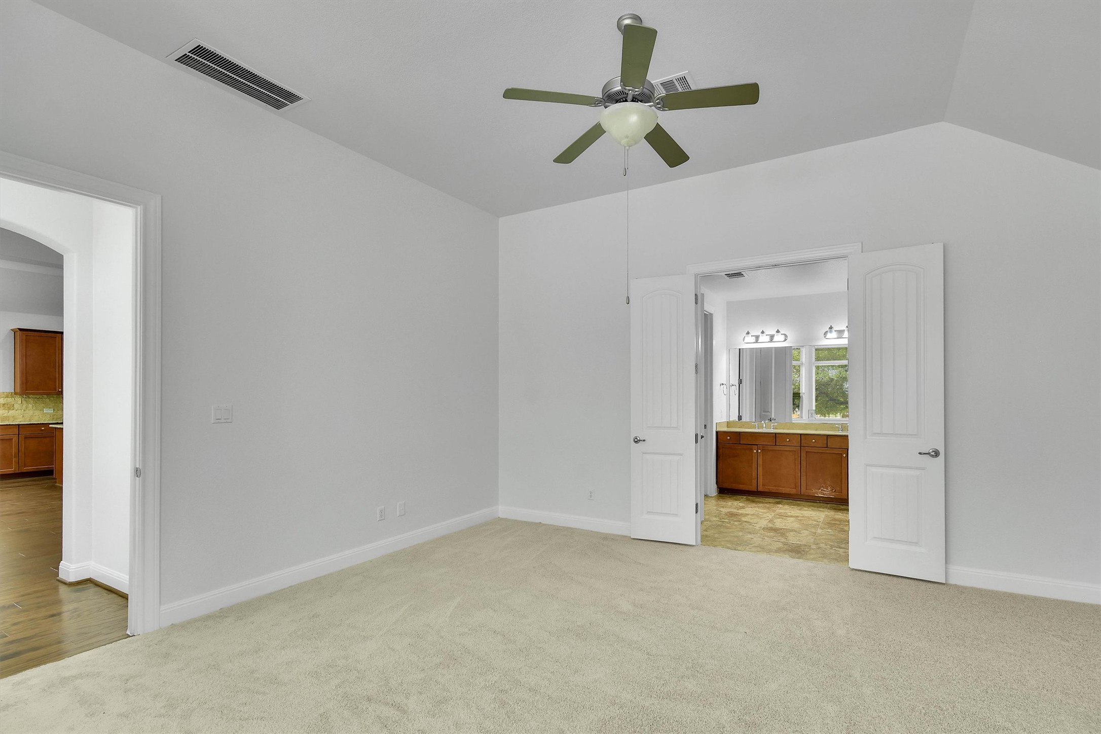 2325 Blended Tree Ranch Drive Leander, TX 78641 - Photo 17 of 35 An airy primary bedroom provides carpeted comfort and convenient access to the private en-suite bathroom.