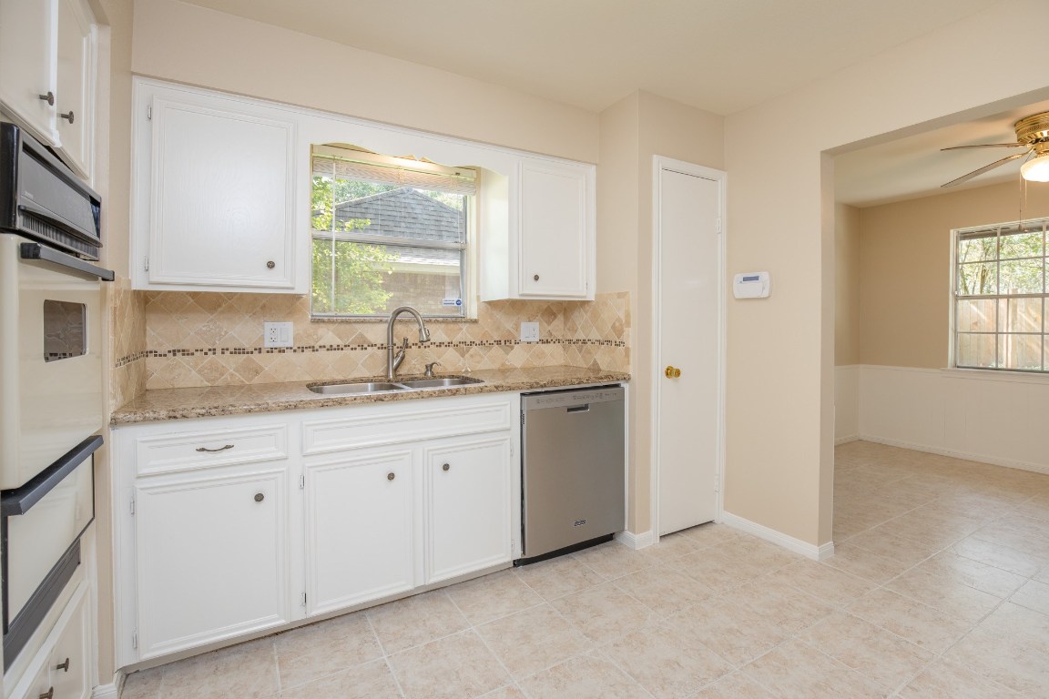 2623 Longleaf Pines Lane Houston, TX 77339 - Photo 15 of 32 a kitchen with granite countertop white cabinets sink and window