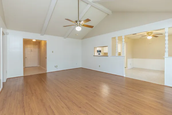 an empty room with wooden floor fan and windows