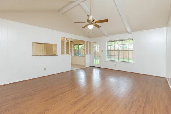 a view of an empty room with wooden floor and a window