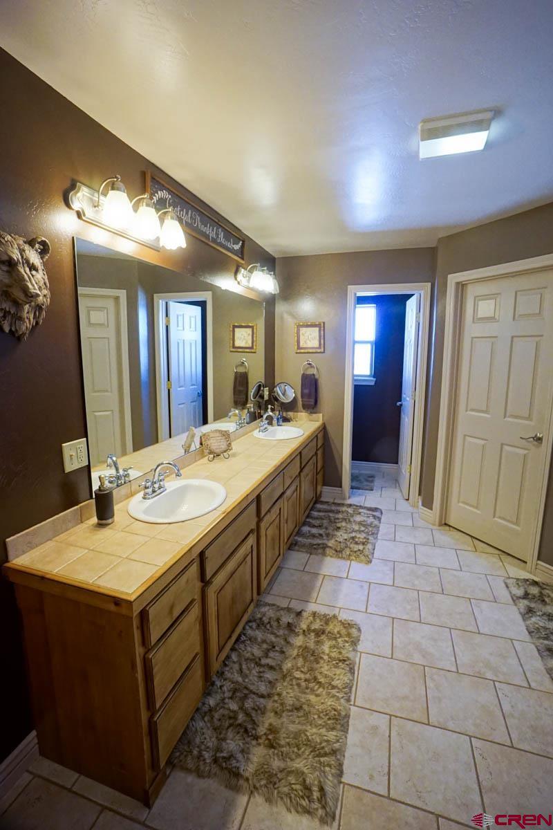 16575 2550th Road Cedaredge, CO 81413 - Photo 16 of 32 a spacious bathroom with a double vanity sink and a mirror