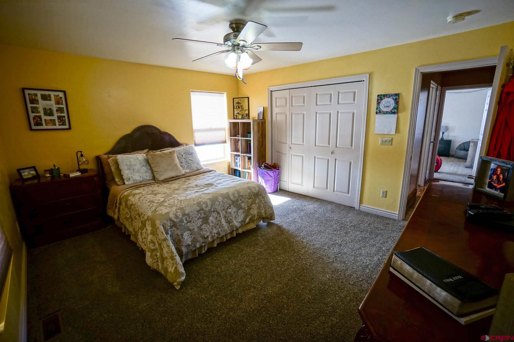 16575 2550th Road Cedaredge, CO 81413 - Photo 19 of 32 a bedroom with a bed and a flat tv screen on dresser