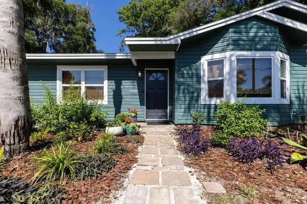 a front view of a house with a yard and potted plants