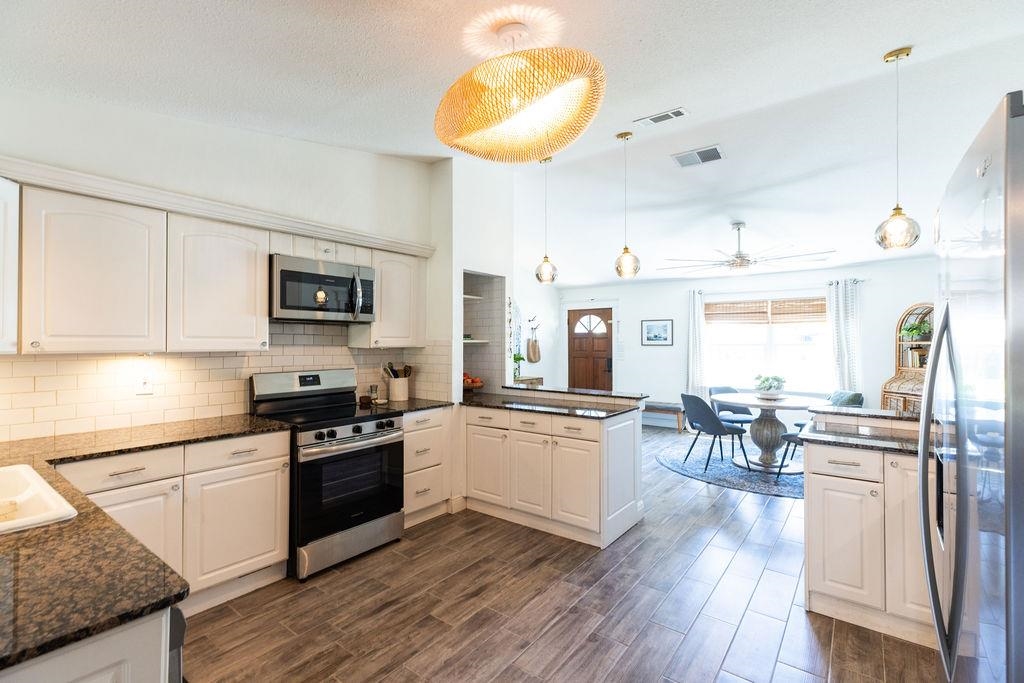 112 Drake Road St. Augustine, FL 32086 - Photo 15 of 59 a kitchen with stainless steel appliances granite countertop a stove top oven a sink a dining table and chairs with wooden floor