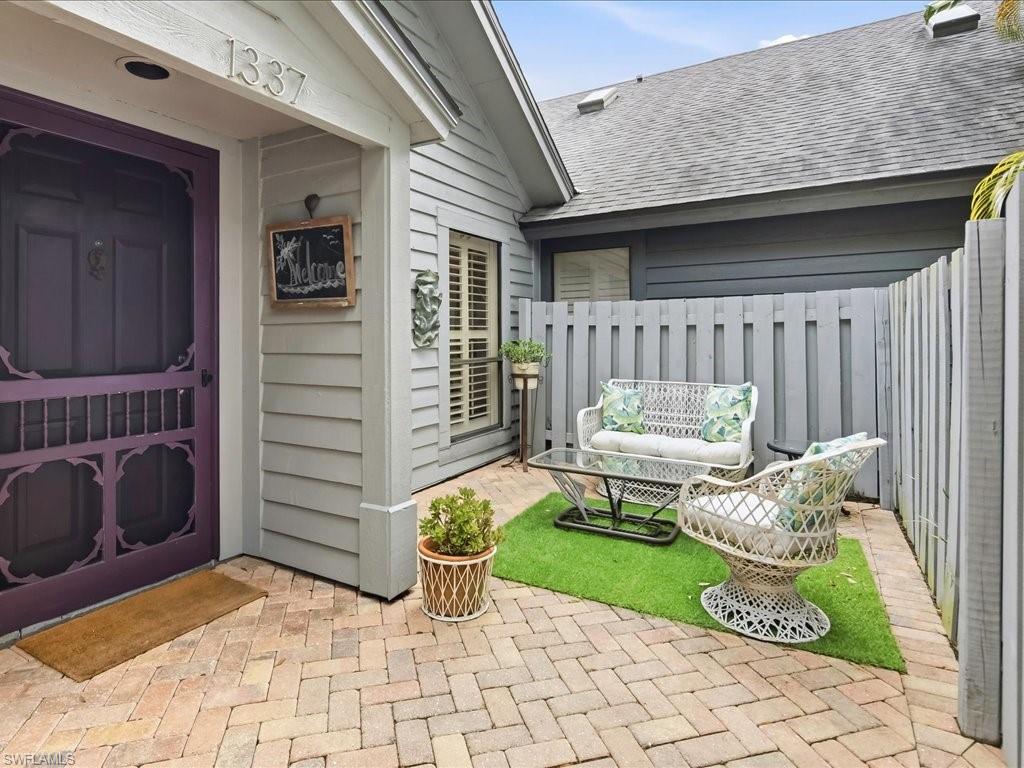 1337 Solana Road Naples, FL 34103 - Photo 3 of 23 Private courtyard entry featuring herringbone brick pavers and a decorative purple screen door