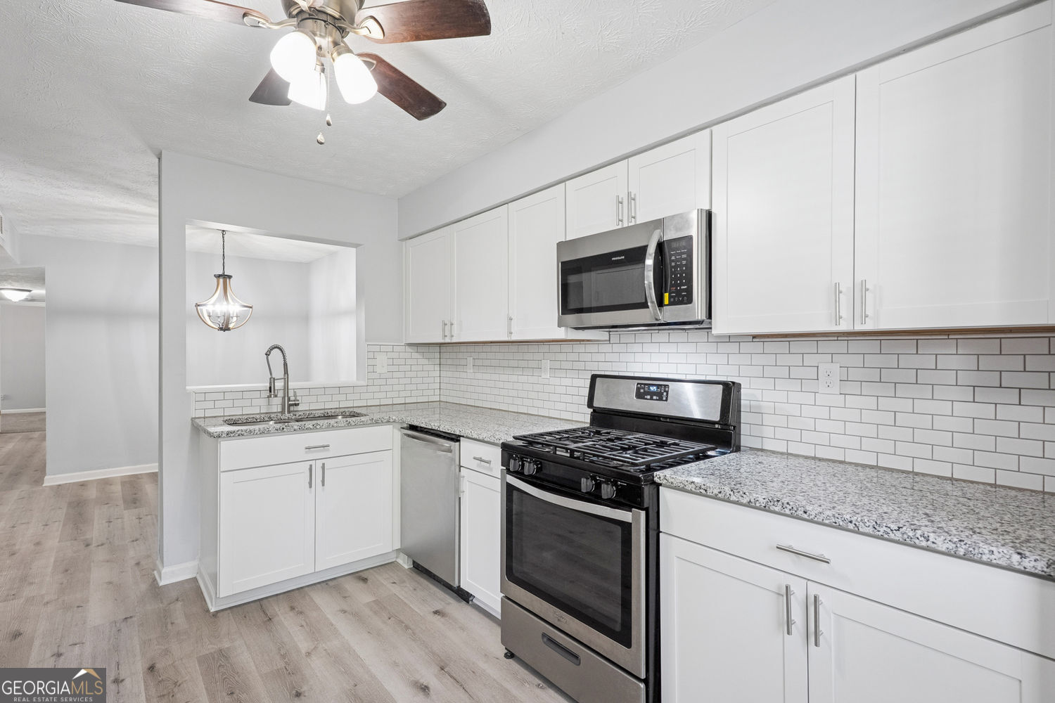 a kitchen with stainless steel appliances granite countertop a sink a stove top oven and cabinetry