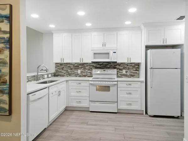 a kitchen with granite countertop white cabinets and white appliances