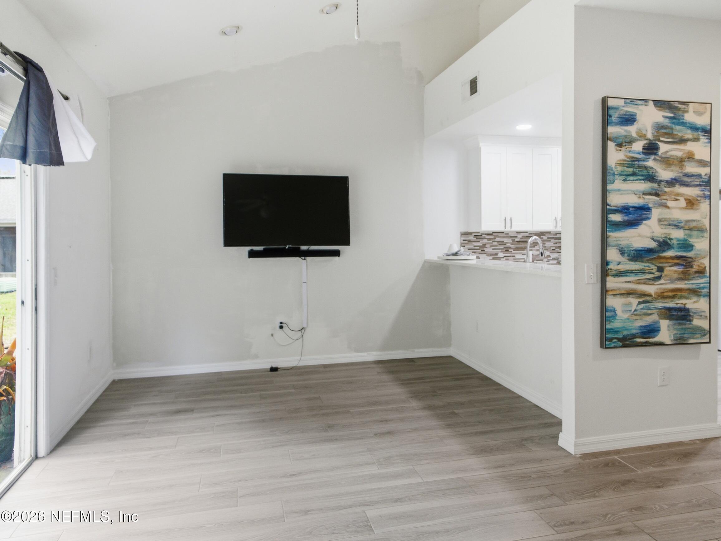 4700 Southwest Archer Road, Unit D27 Gainesville, FL 32608 - Photo 9 of 34 a view of a livingroom with wooden floor and a flat screen tv