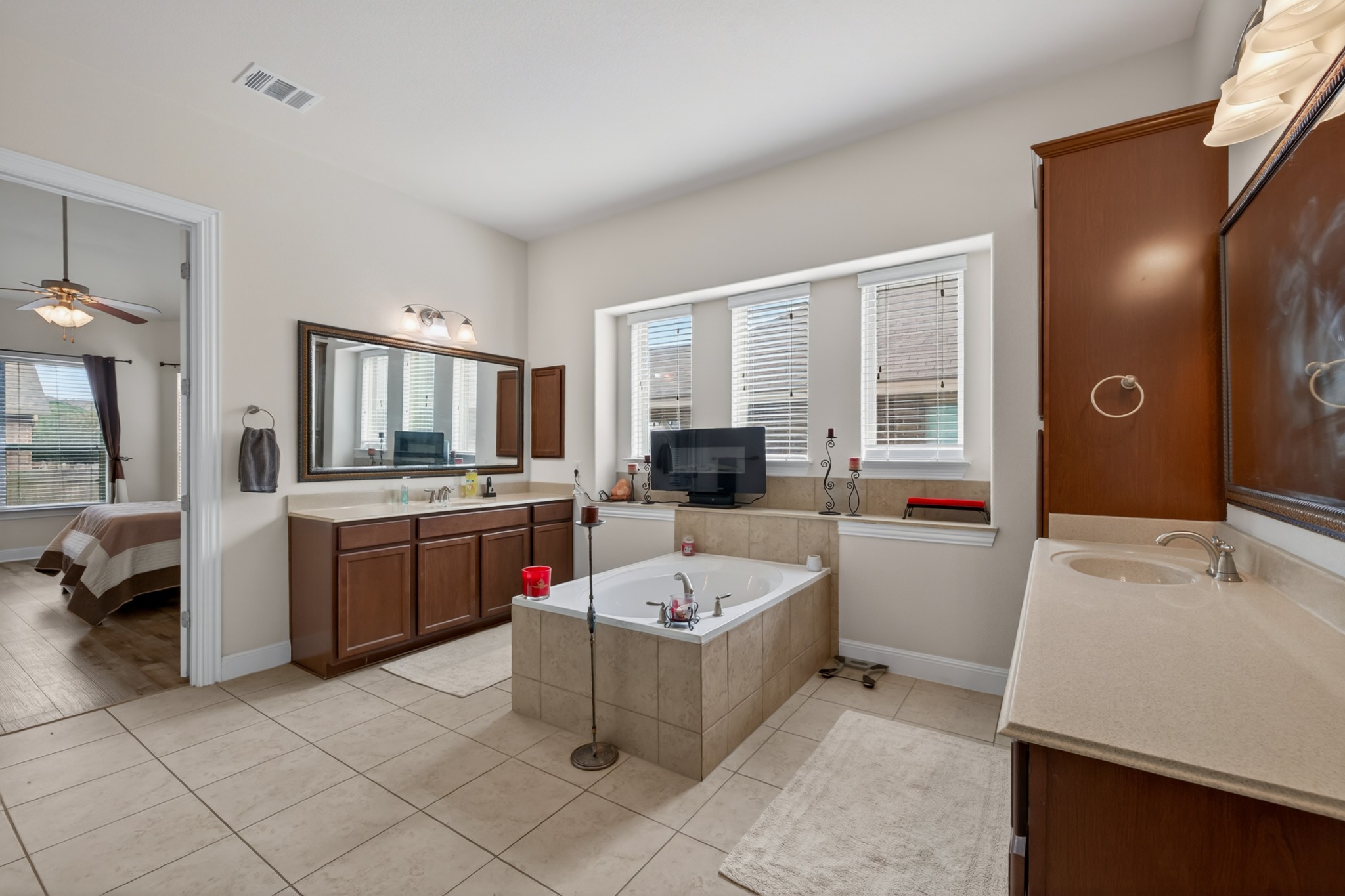 1017 Tabernash Leander, TX 78641 - Photo 23 of 38 Spacious bathroom featuring a built-in tub with tile surround, dual vanities with light-toned countertops, and light-toned tile flooring