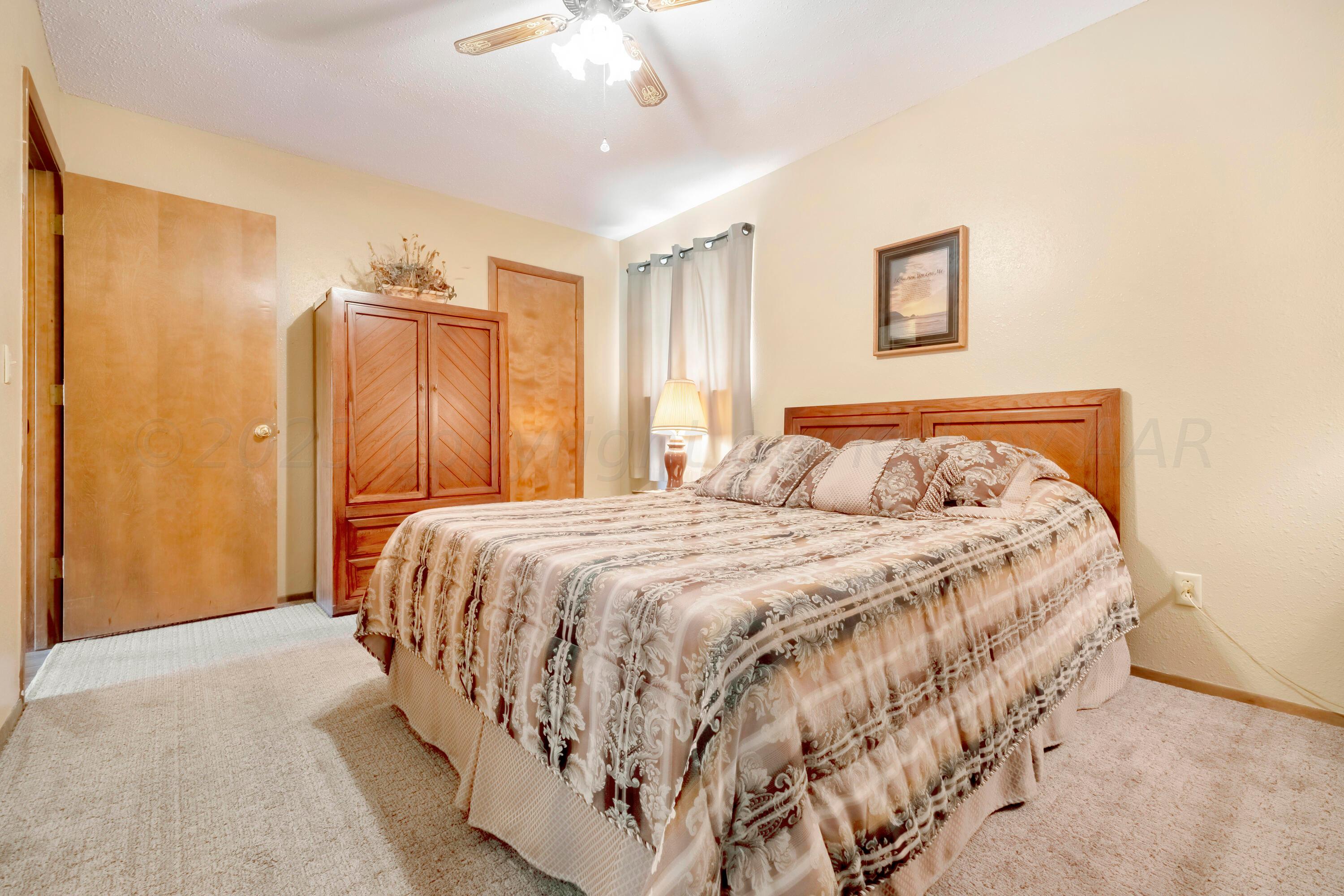 200 West Santa Fe Street Allison, TX 79003 - Photo 17 of 32 a bedroom with a bed and a chandelier