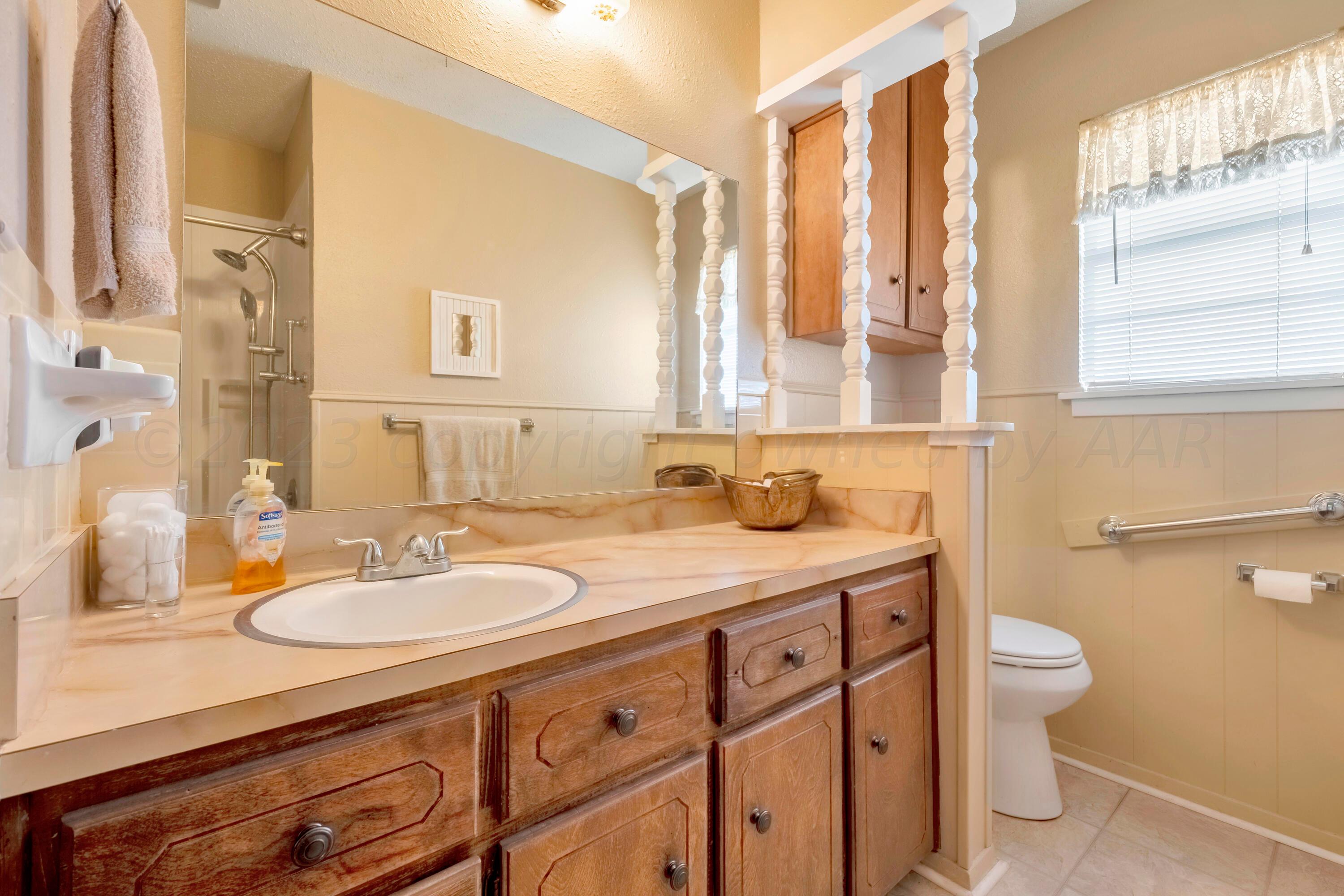200 West Santa Fe Street Allison, TX 79003 - Photo 18 of 32 a bathroom with a granite countertop sink a toilet a mirror and a window