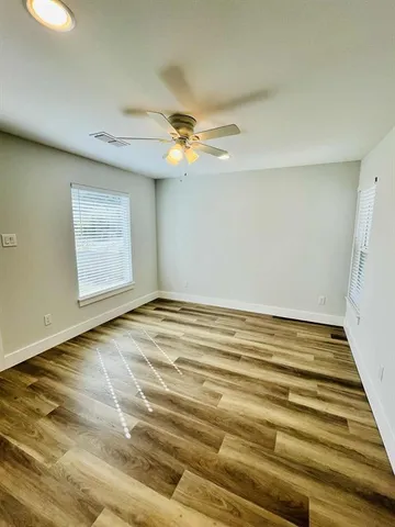 a view of a room with a ceiling fan and wooden floor