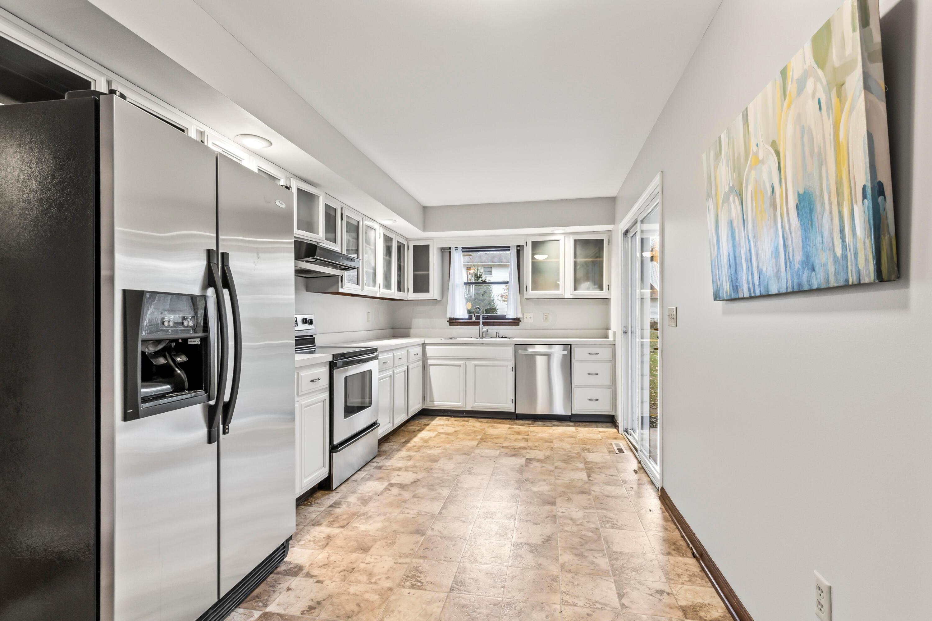 7020 Rieber Street Columbus, OH 43085 - Photo 14 of 40 • New neutral vinyl flooring ~ 2006 • Grey painted walls • Raised panel, white painted cabinets with glass fronts • New Whirlpool® refrigerator ~ 2017 • New Whirlpool® electric range ~ 2017 • Allure® rangehood • New Kenmore® dishwasher ~ 2017 • Double bowl, stainless steel sink with sprayer • New disposal • Can lighting • New sliding doors to screened porch • Planning desk • Buffet/media center • Pantry closet • Sliding doors to Screened Porch